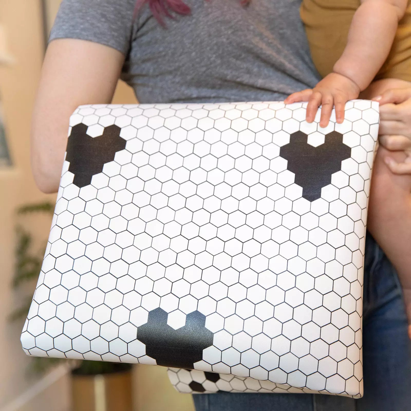 Penny Tile Black and White Heart pattern highchair mat folded over womans arm