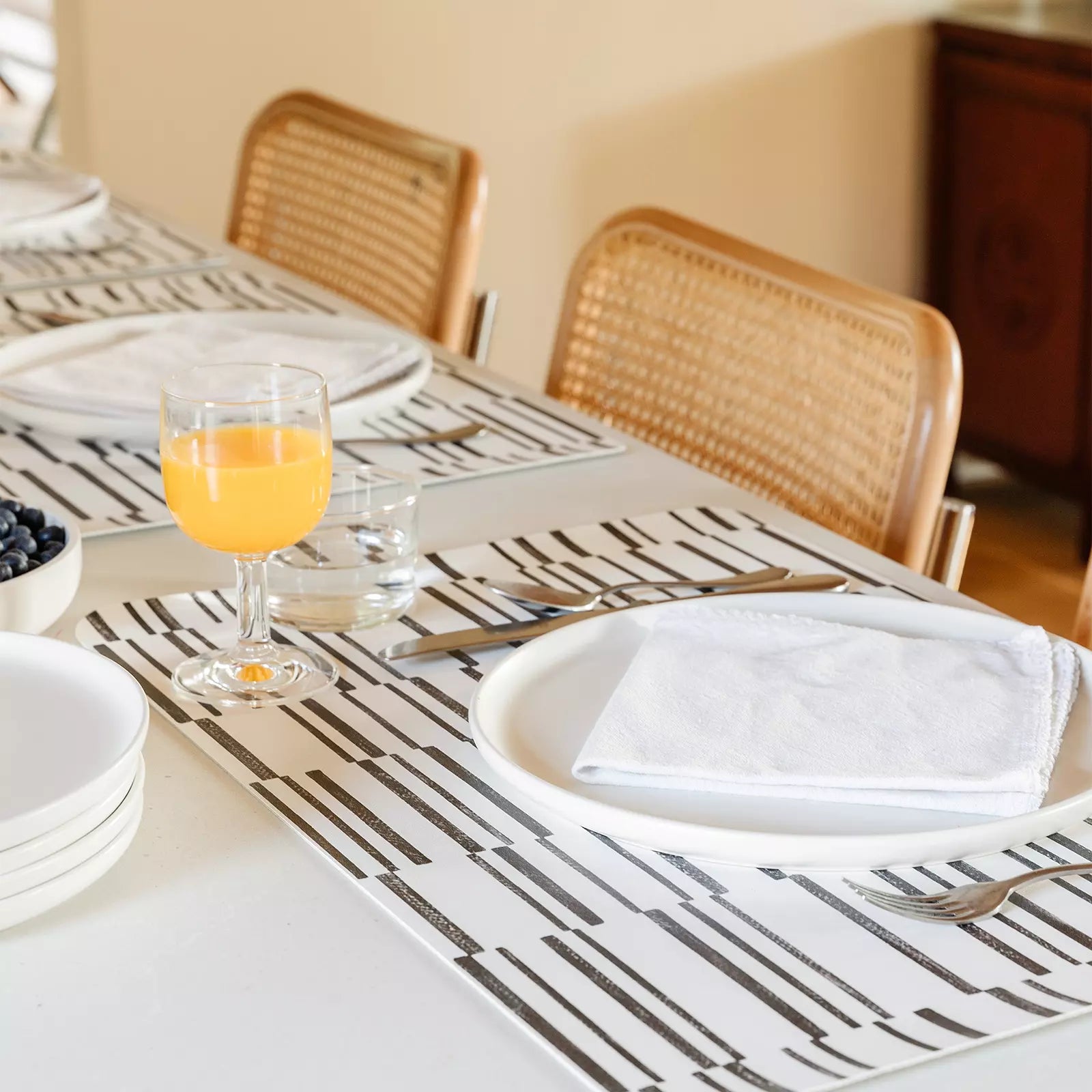 Nara Black and White Striped place mat  at table setting with plate, napkin and orange juice