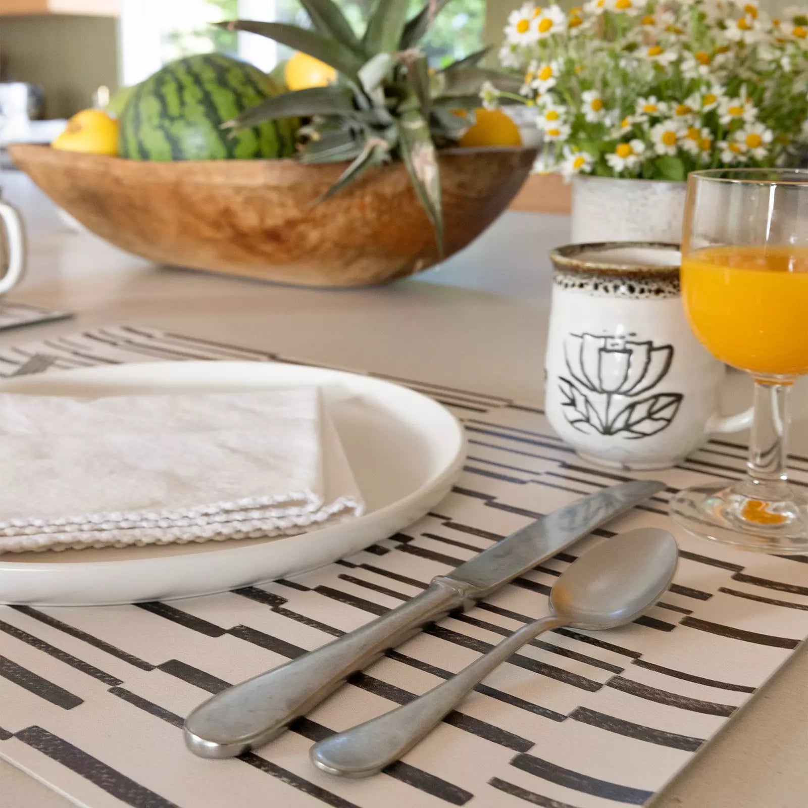 Nara Black and White Striped place mat at table setting with plate, napkin and orange juice