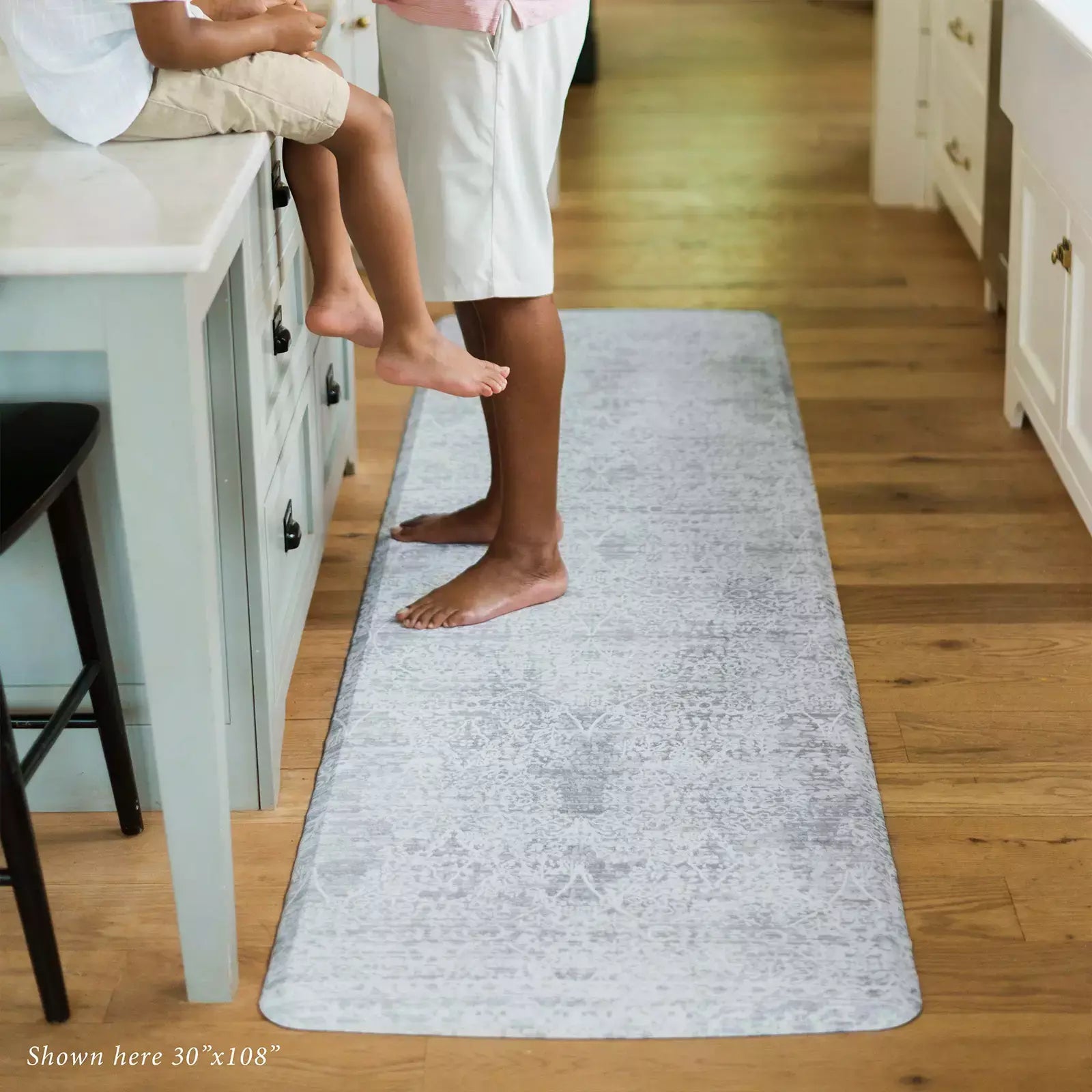 Gray neutral boho print kitchen mat with man and child in kitchen shown in 30x108