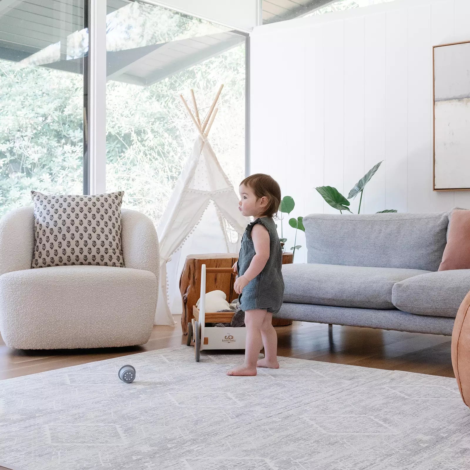 Gray and white minimal boho baby play mat shown in living room with toddler playing with toys