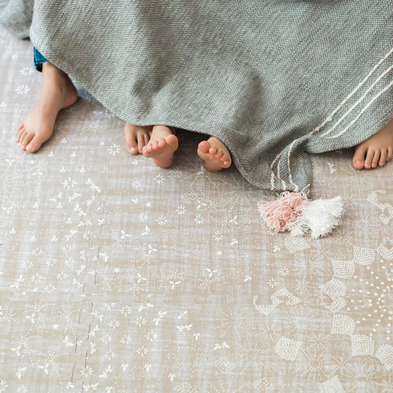 Sand Castle beige play mat with kids feet under blanket